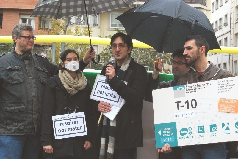 Imatge de la roda de premsa on s'ha utilitzat alguns símbols que descriuen el divorci entre les polítiques ambientals i les accions reals de l'Ajuntament i la Generalitat: el tarifazo al transport públic i el boicot municipal a la connexió dels tramvies.